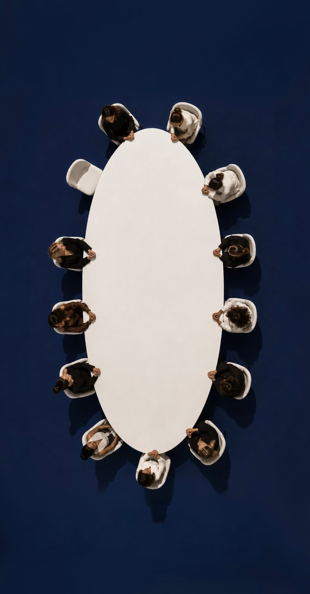 Twelve women seated around an oval table, seen from above